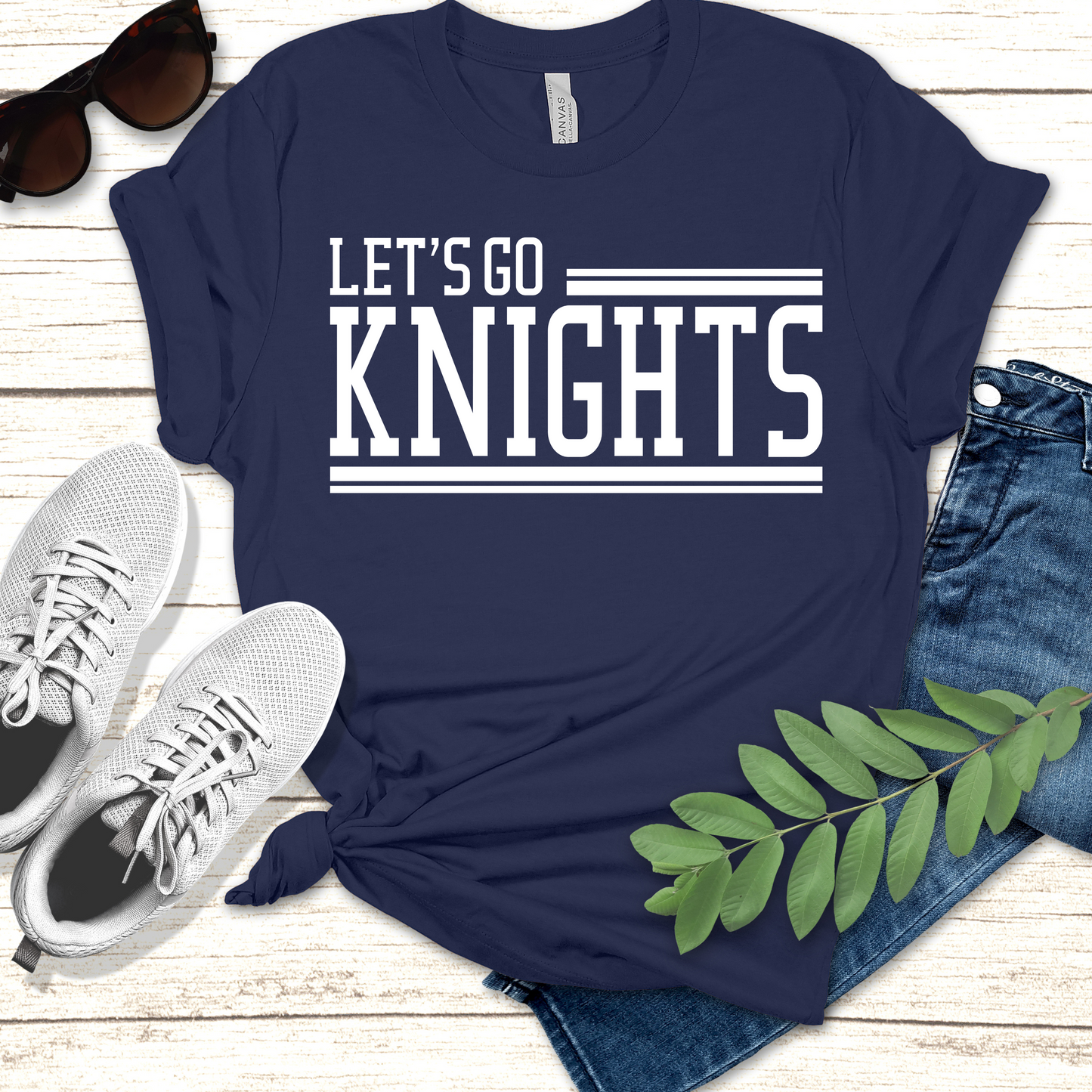 Navy blue t-shirt with 'LET'S GO KNIGHTS' text, paired with sneakers and jeans on a wooden surface. Knights School Spirit Shirt - Let's Go Knights - Knights Spirit Tee