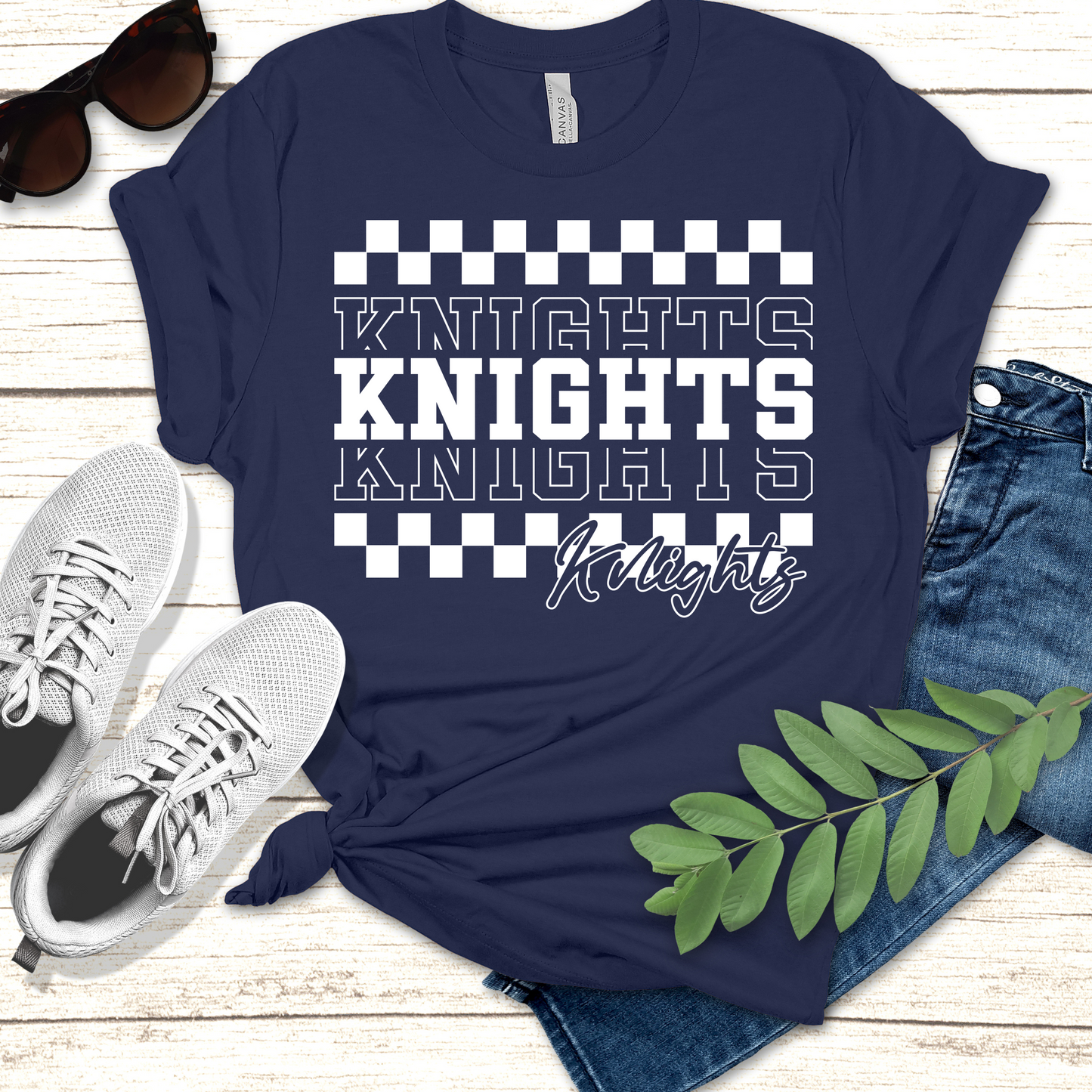 Navy blue t-shirt with 'Knights' text design, paired with sneakers and jeans on a wooden surface. Knights School Spirit Shirt - Knights Checkered - School Pride T-Shirt