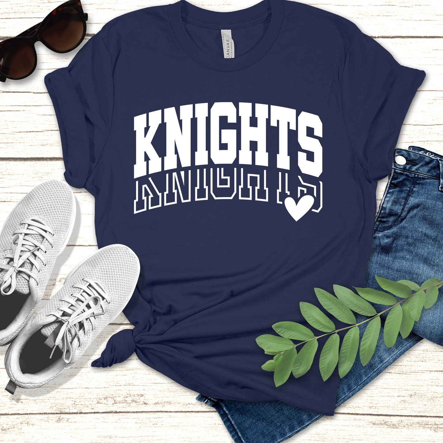 Navy blue t-shirt with 'KNIGHTS' text, sunglasses, sneakers, and jeans on a wooden surface. Knights School Spirit Shirt - Knights Varsity - Knights Spirit Tee