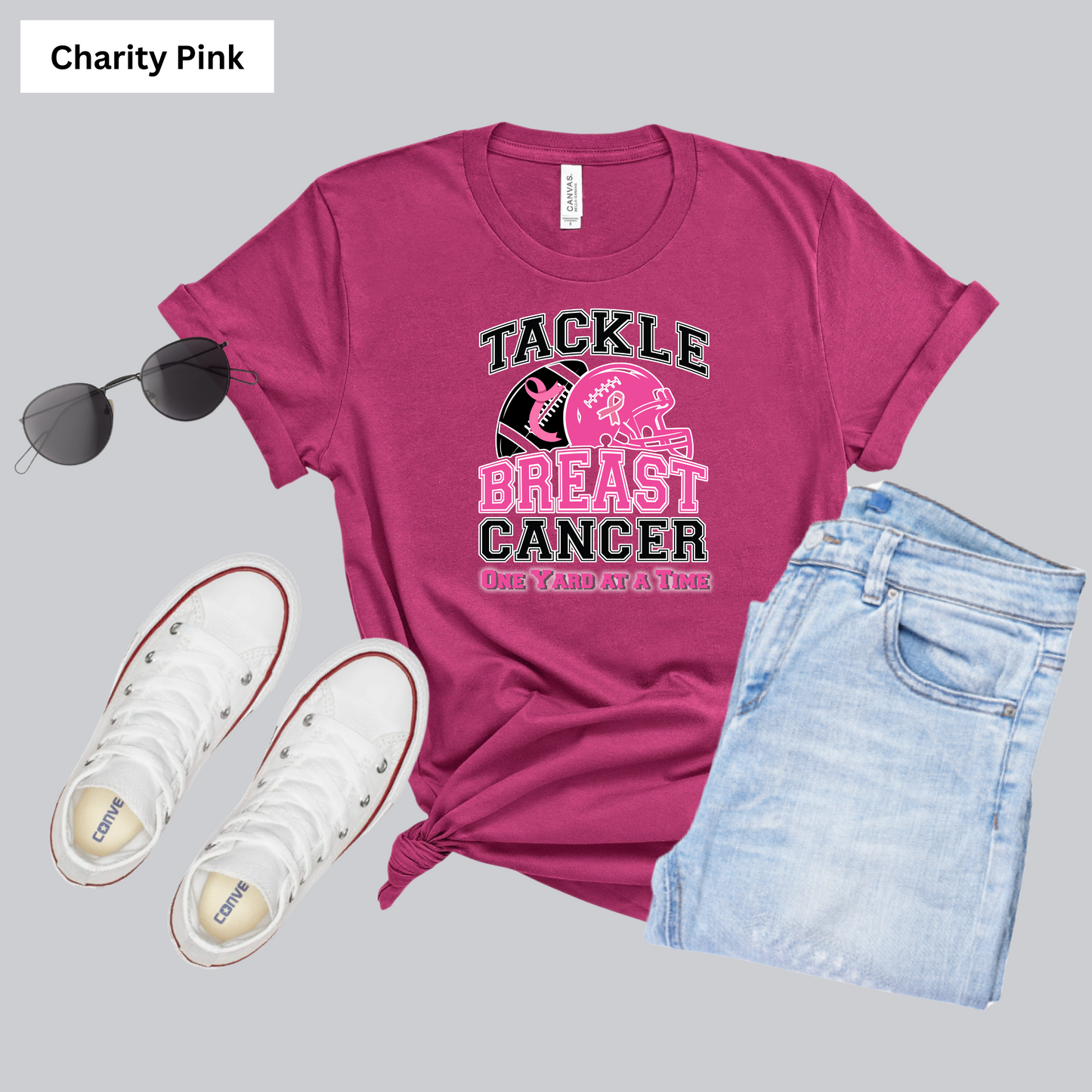 Pink t-shirt with 'Tackle Breast Cancer' text, sunglasses, white sneakers, and denim shorts on a gray background. October Awareness Shirt - Tackle for a Cause One Yard at a Time Tee