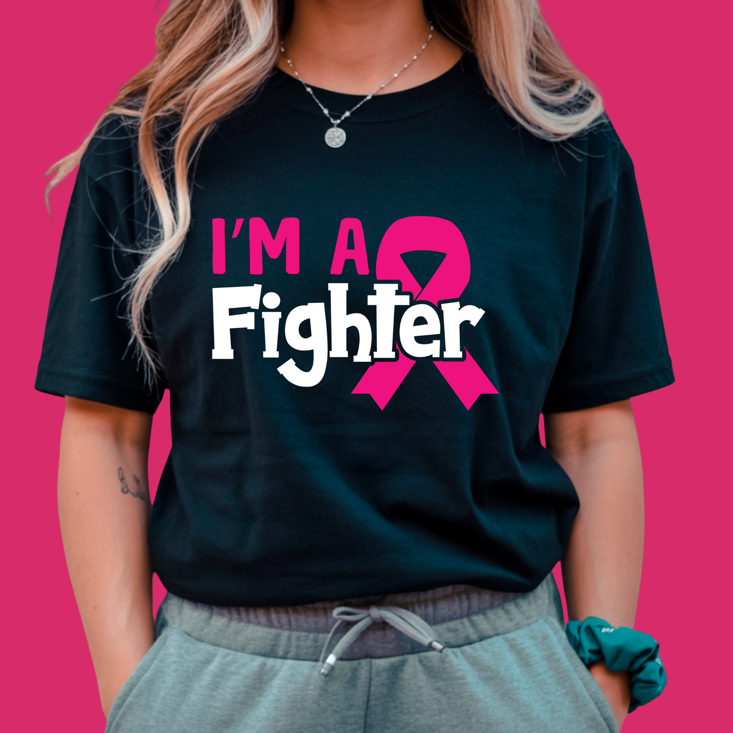 Person wearing a black t-shirt with 'I'm a Fighter' and a pink ribbon design on a pink background Pink Ribbon Tee: I'M A FIGHTER - Powerful Empowerment T-shirt