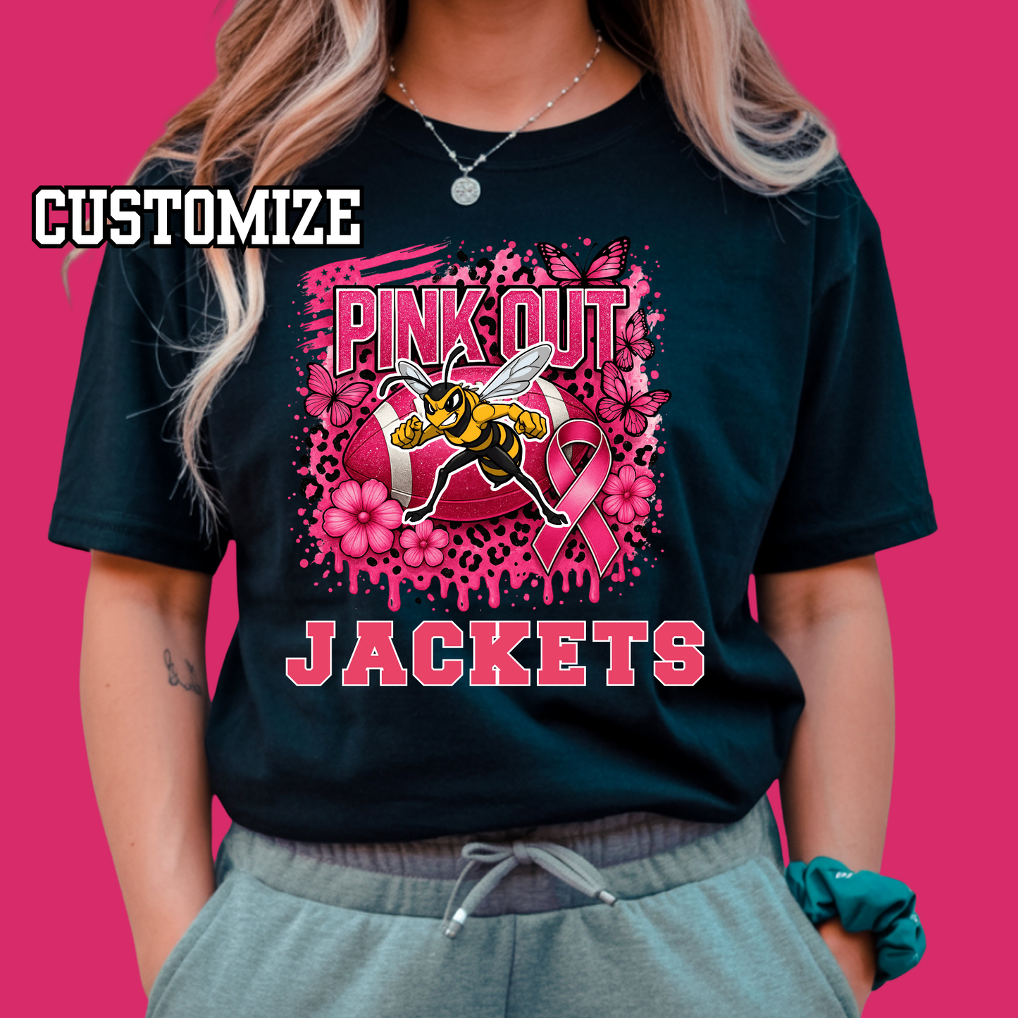 Person wearing a black t-shirt with 'Pink Out Jackets' design featuring a bee and pink ribbon on a pink background. Custom Pink Out Football Tee - Custom Pink Out Mascot T-Shirt