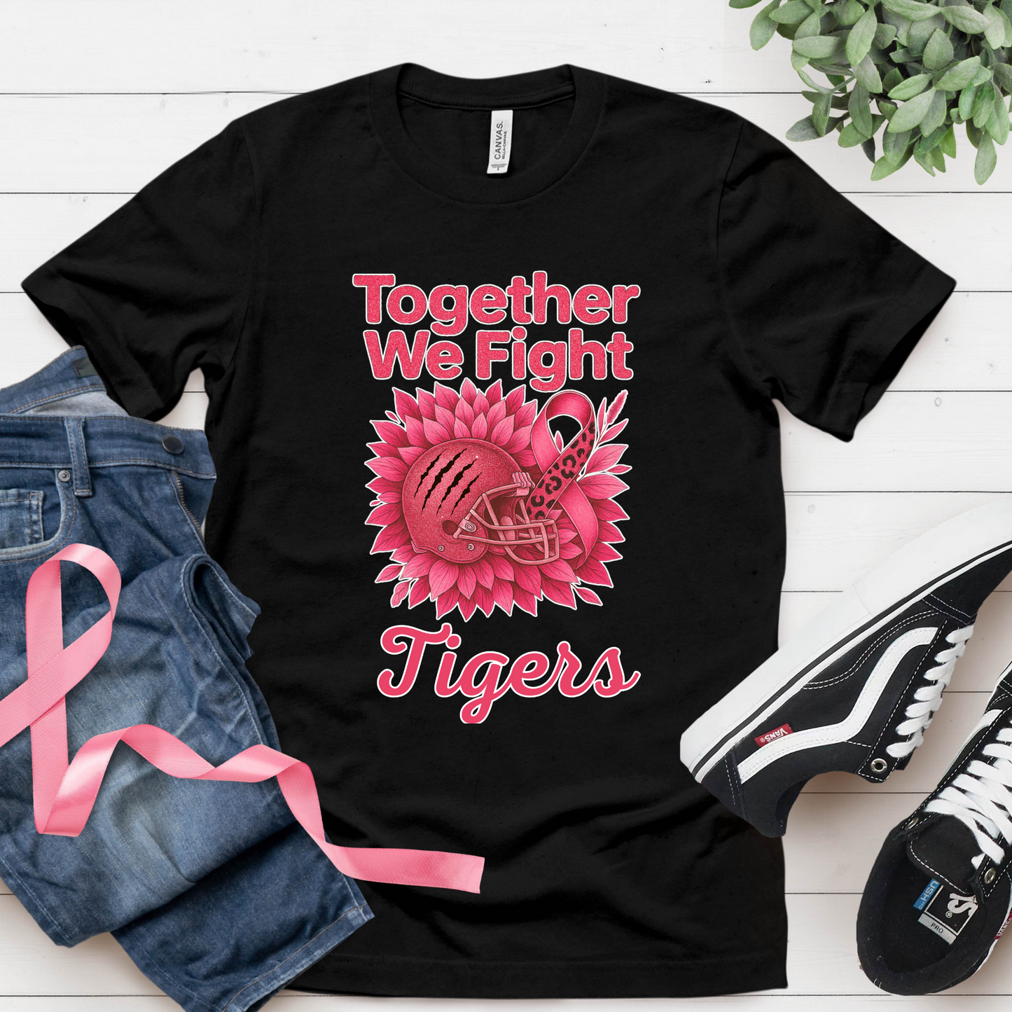 Black t-shirt with pink design and text, placed on a white surface with jeans and sneakers. Custom Pink Ribbon Football Tee: Together We Fight - Custom Mascot