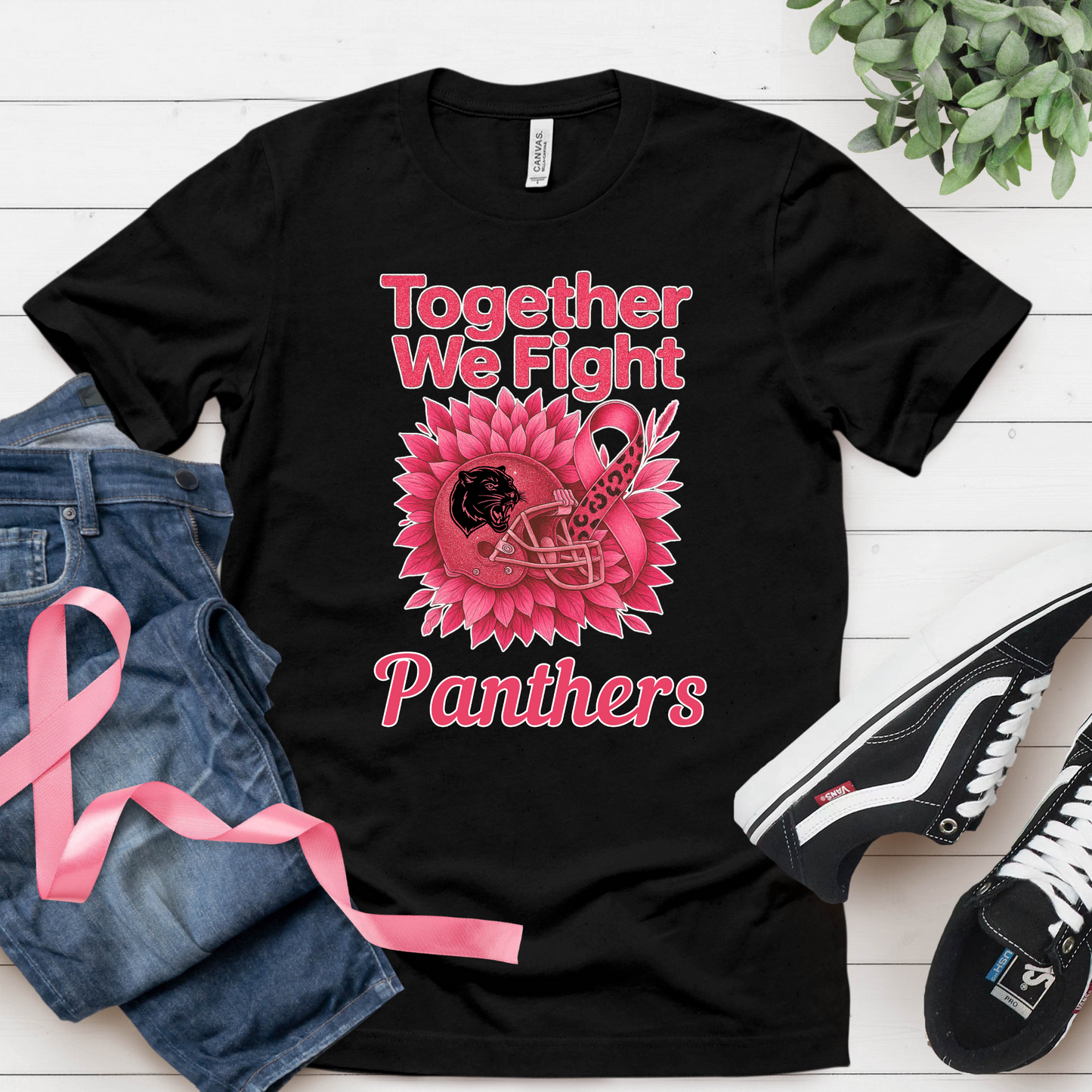 Black t-shirt with pink graphic and text 'Together We Fight Panthers' on a white wooden surface with jeans and sneakers. Custom Pink Ribbon Football Tee: Together We Fight - Custom Mascot
