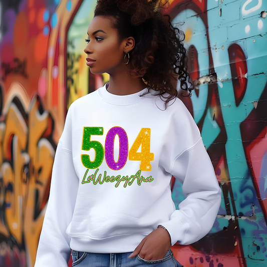 Person wearing a white sweatshirt with colorful text in front of a graffiti wall.