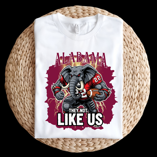White t-shirt with Alabama-themed graphic featuring an elephant and text on a woven surface. Alabama Football T-Shirt "They Not Like Us" Alabama Game Day Shirt