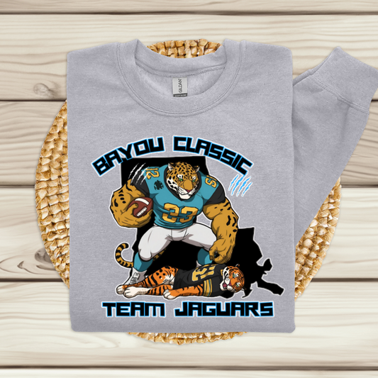 Gray sweatshirt with 'Bayou Classic Team Jaguars' design featuring a tiger and football player on a woven mat. Bayou Classic Team Jaguars: Bayou Classic HBCU Jaguars Game Day Sweater