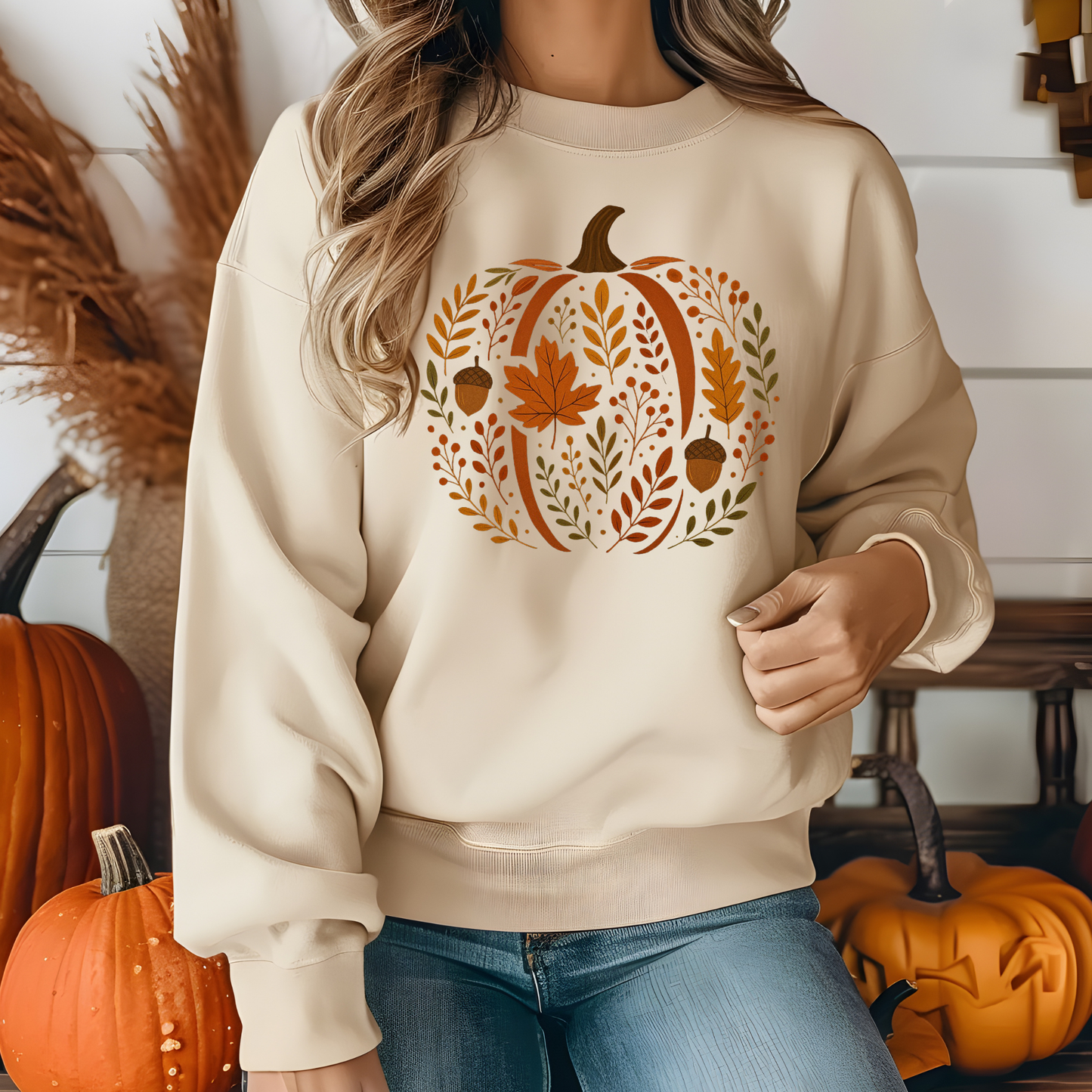 Person wearing a beige sweatshirt with a pumpkin design, standing in front of pumpkins. Chic Botanical Pumpkin Sweatshirt: Fall Floral Crewneck Sweatshirt
