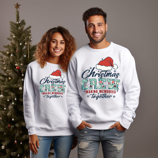 Two people wearing matching white sweatshirts with 'Christmas Crew' text in front of a decorated Christmas tree.
