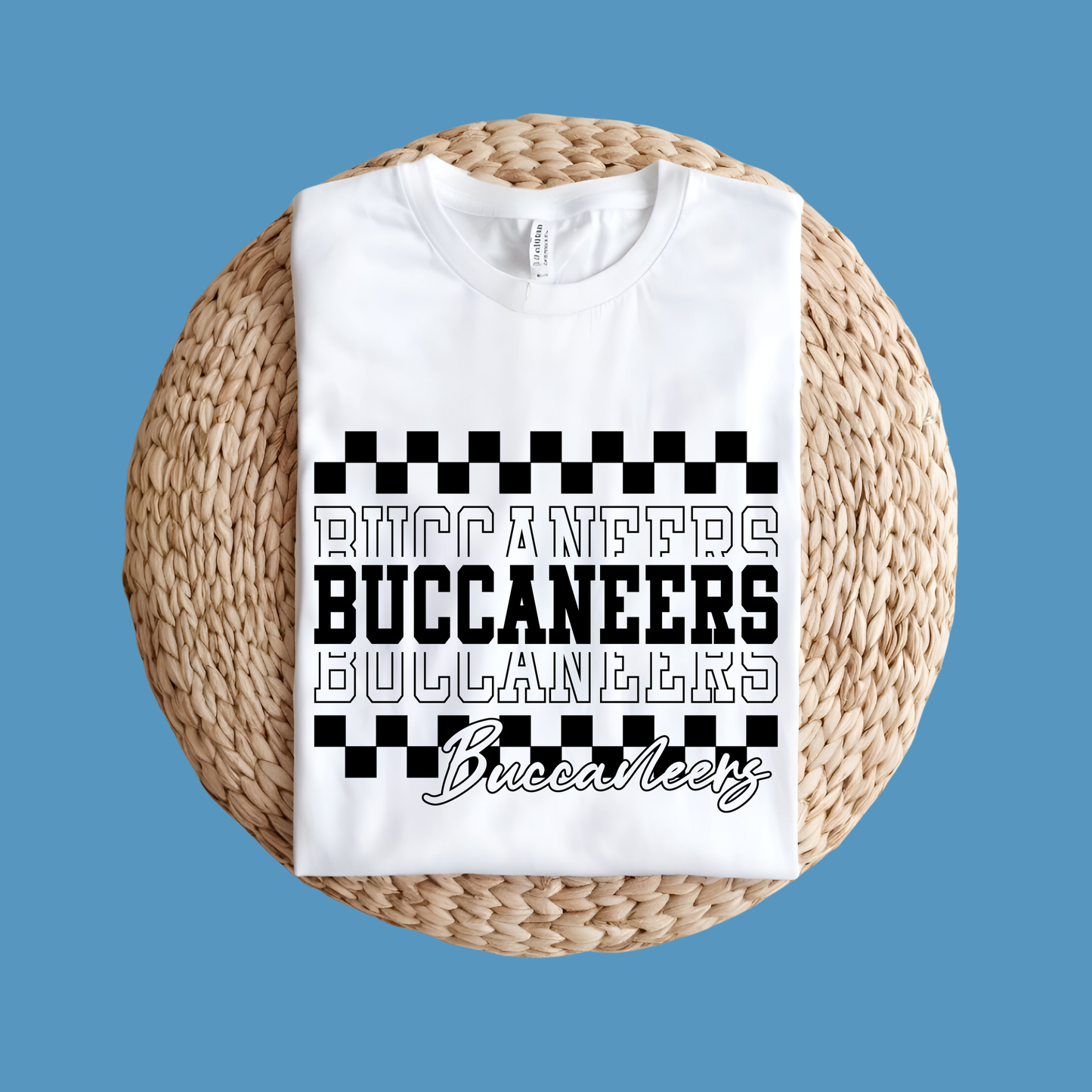 White t-shirt with 'Buccaneers' text design on a woven mat against a blue background Custom Mascot Shirt - Buccaneers Layered Game Day Cool School Spirit Tee
