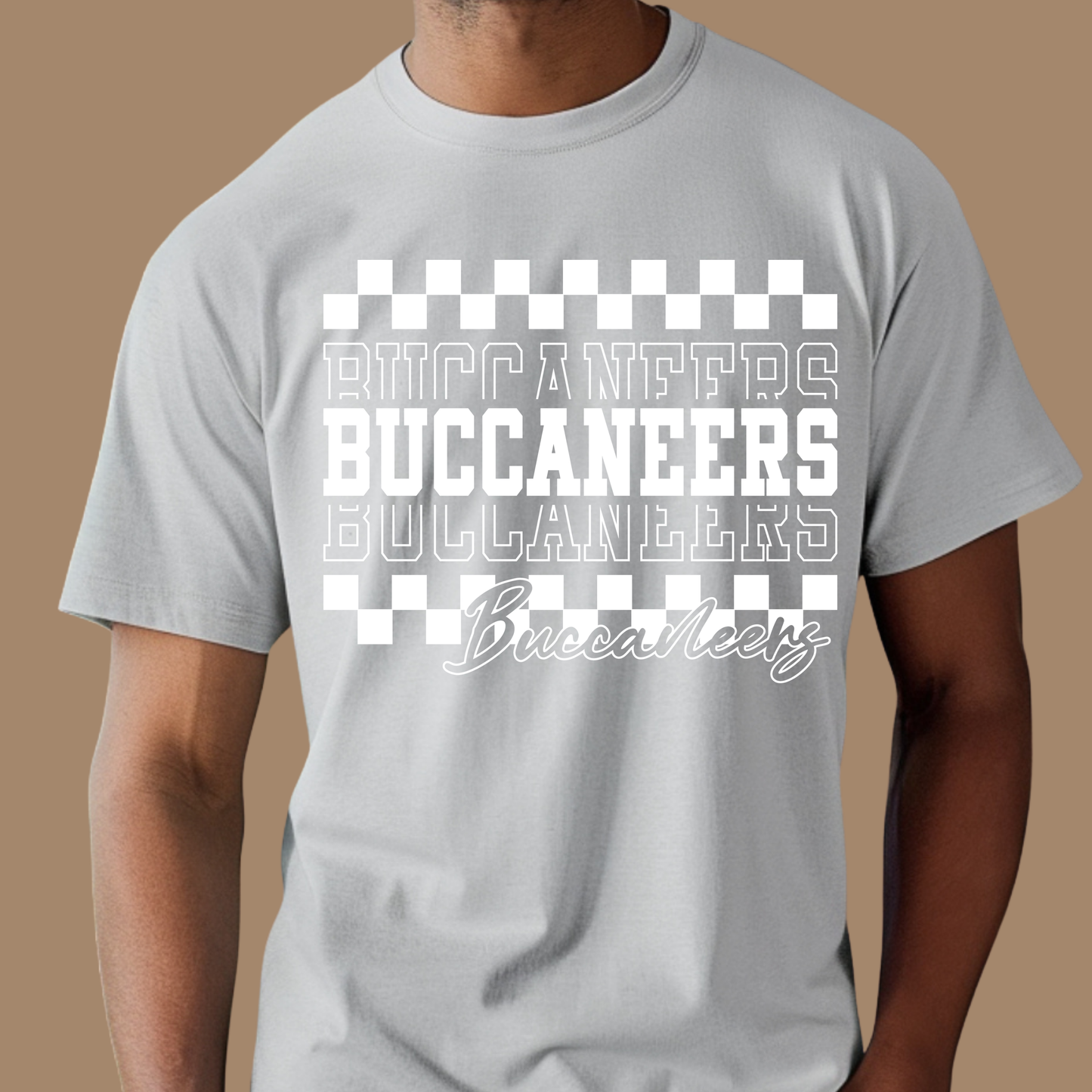 Gray t-shirt with 'Buccaneers' text and checkered design on a brown Custom Mascot Shirt - Buccaneers Layered Game Day Cool School Spirit Tee background