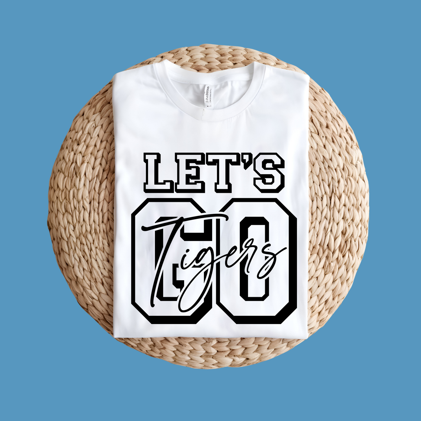 White t-shirt with 'Let's Go Tigers' text on a woven mat against a blue background, Custom Mascot Shirt - Let's Go Tigers Game Day Spirit Wear