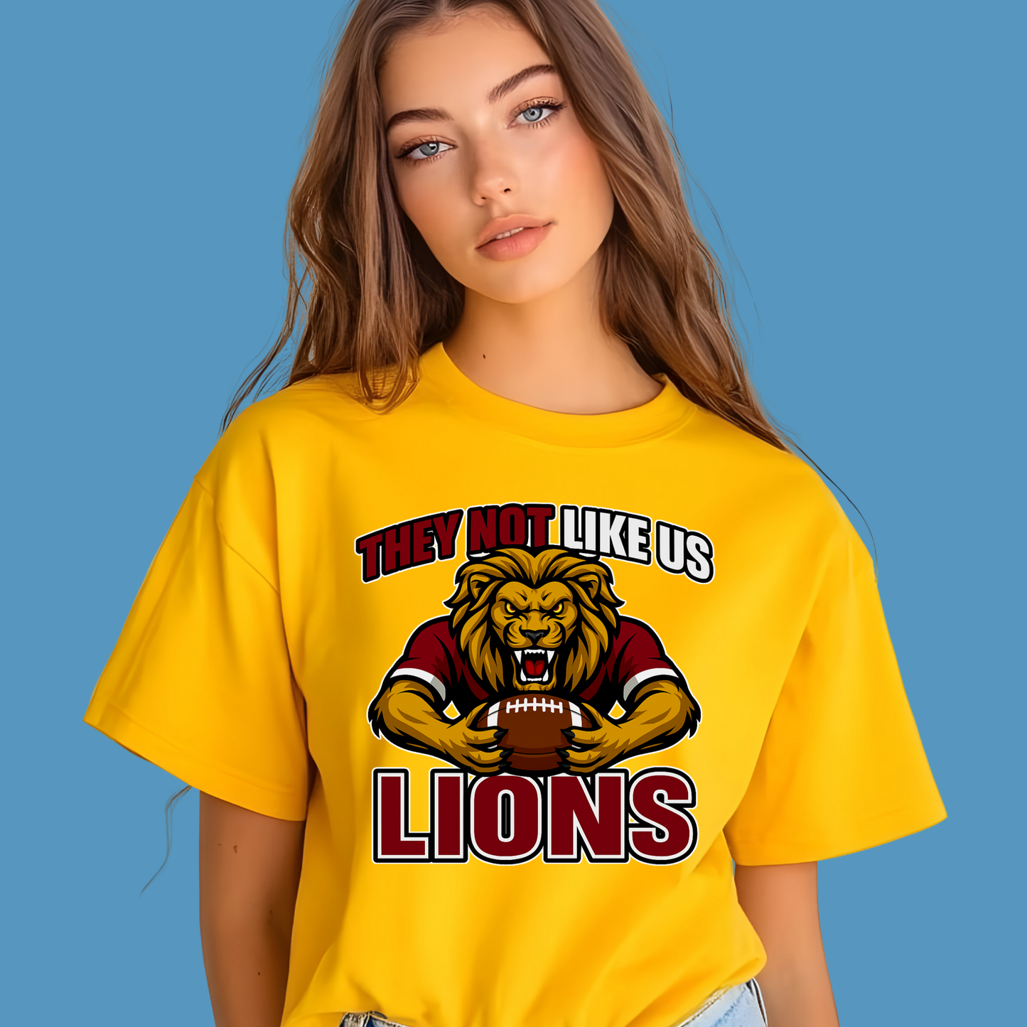 Person wearing a yellow t-shirt with a lion graphic and text on a blue Custom Mascot Shirt - Lions They Not Like Us Game Day Spirit Teebackground