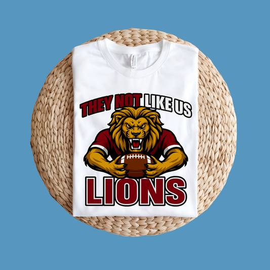 White t-shirt with lion graphic and text on a woven surface Custom Mascot Shirt - Lions They Not Like Us Game Day Spirit Tee