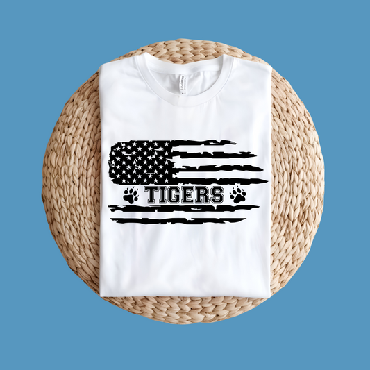 White t-shirt with American flag and 'Tigers' text on a woven surface with blue background, Custom Mascot Shirt - Tigers American Flag School Spirit Tee Shirt