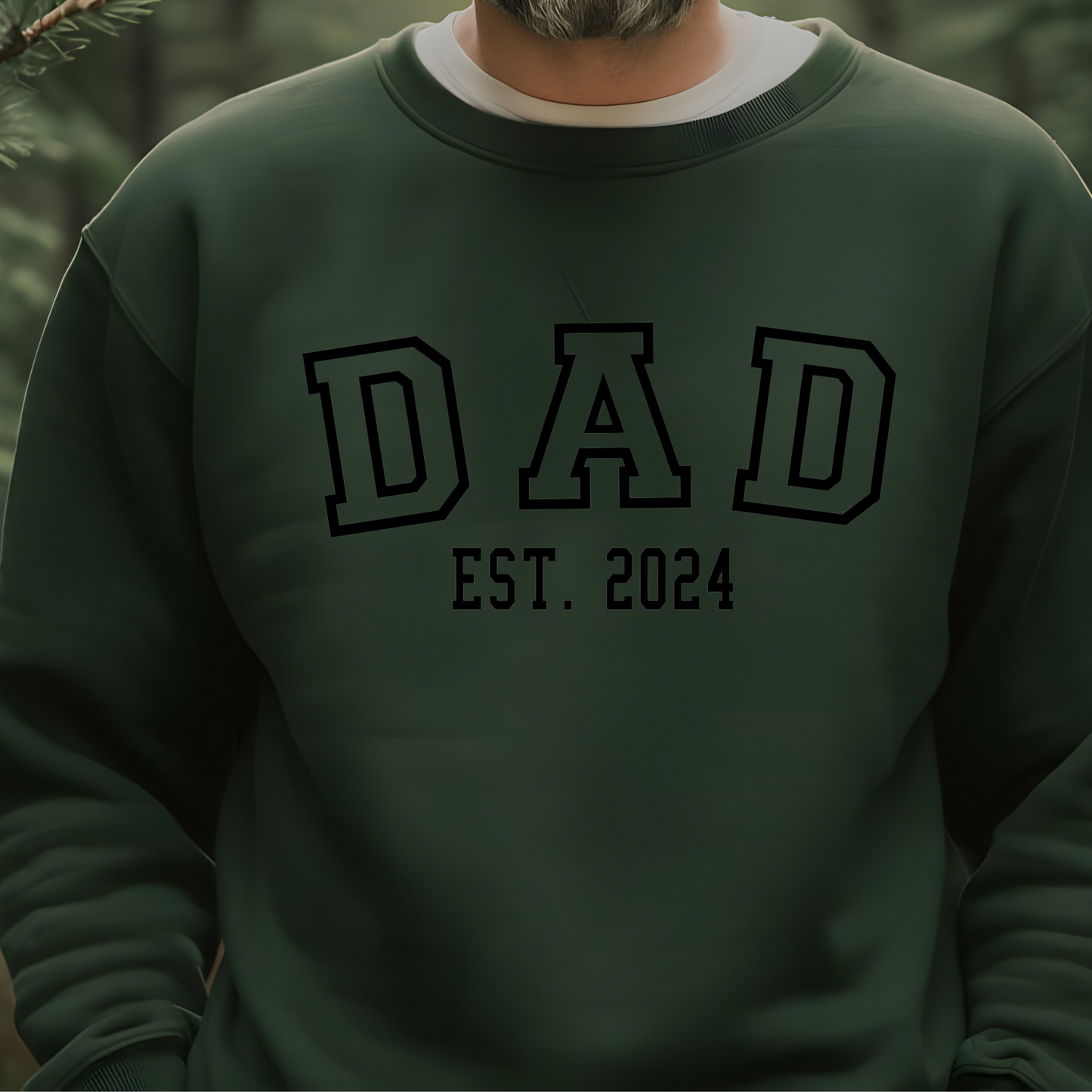 Men wearing a white sweatshirt with "DAD" in bold letters and "EST. 2024" below, featuring a heart graphic with kid names personalized on the sleeve. New Dad sweater.