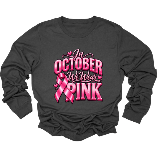 A dark charcoal gray long-sleeve t-shirt with a pink graphic on the front that reads 'In October We Wear Pink' with a pink ribbon design, displayed on a clean white background.