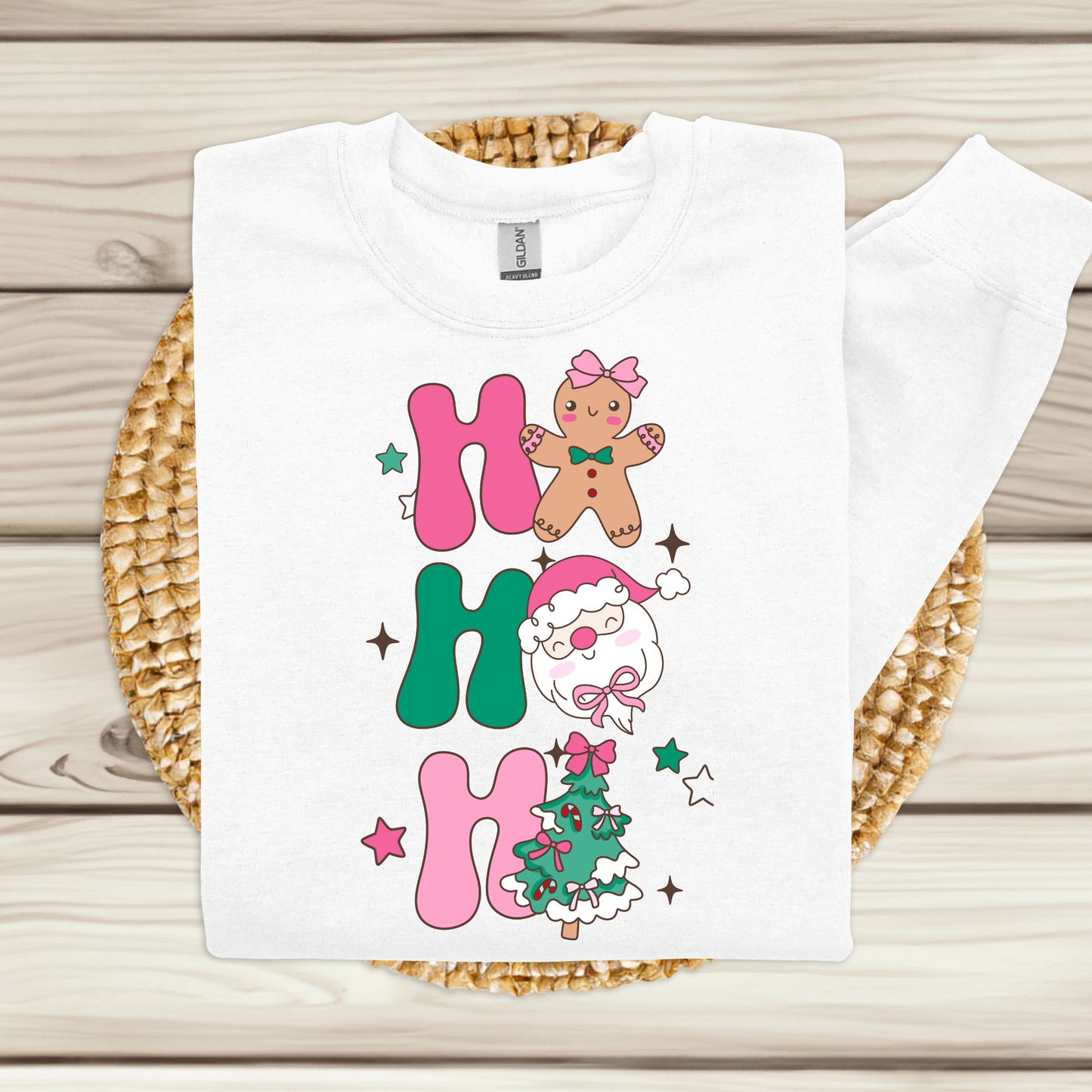 White t-shirt with Christmas-themed design featuring gingerbread man, snowman, and tree on a woven mat.