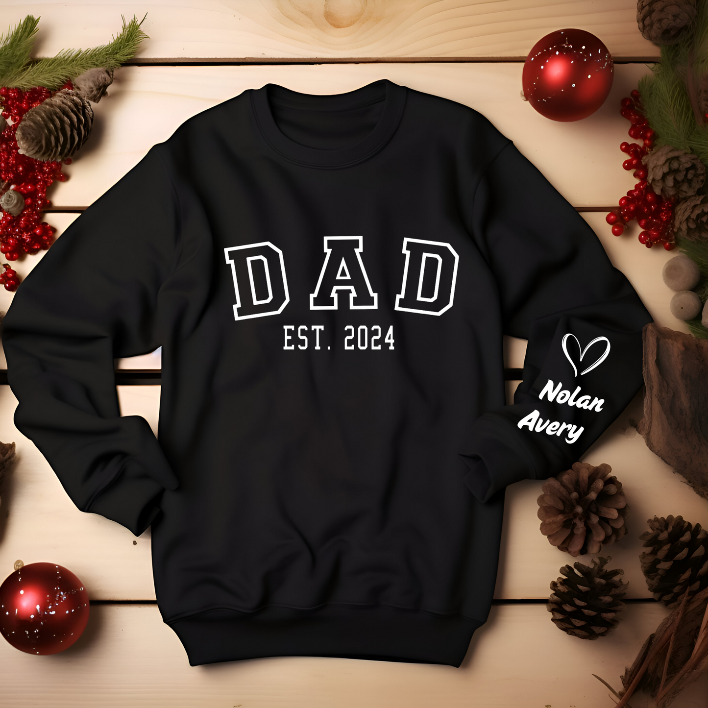 Man wearing a black sweatshirt with "DAD" in bold letters and "EST. 2024" below, featuring a heart graphic with kid names personalized on the sleeve. New Dad sweater.