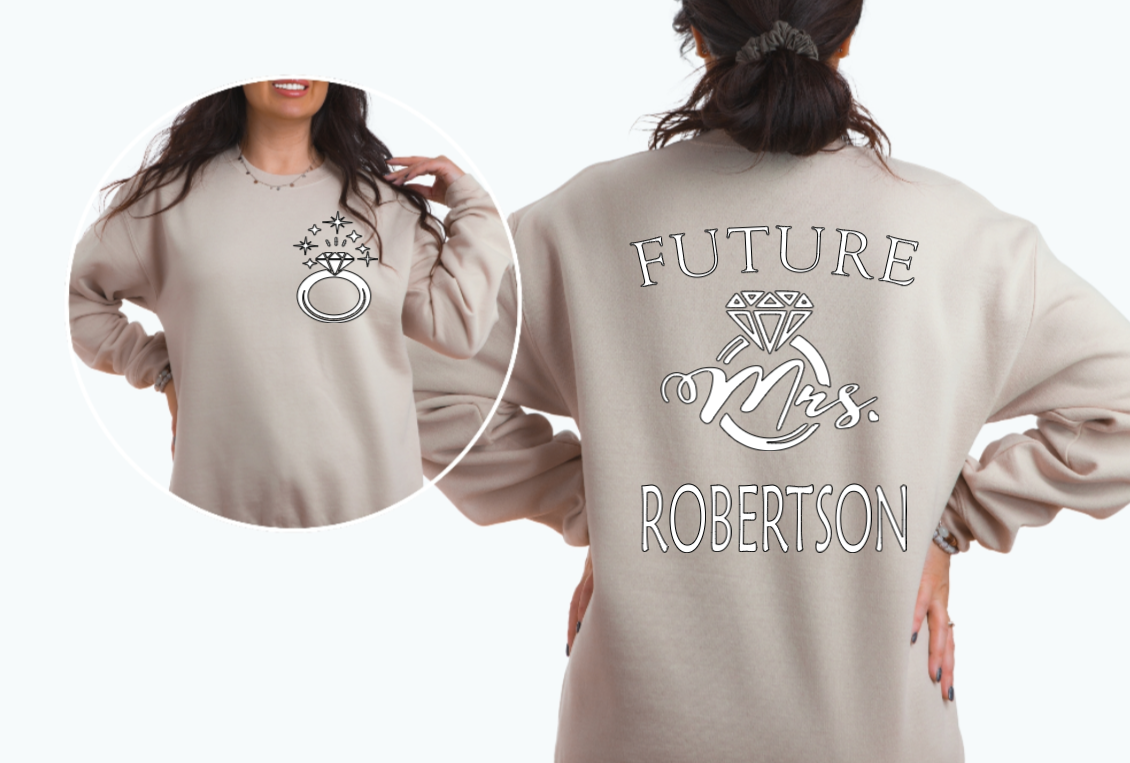Woman wearing sand sweater with FUTURE Mrs. on the back with bling ring on the front indicating engagement announcement shirt for bridal shower or engagement party and gift for new bride to be.