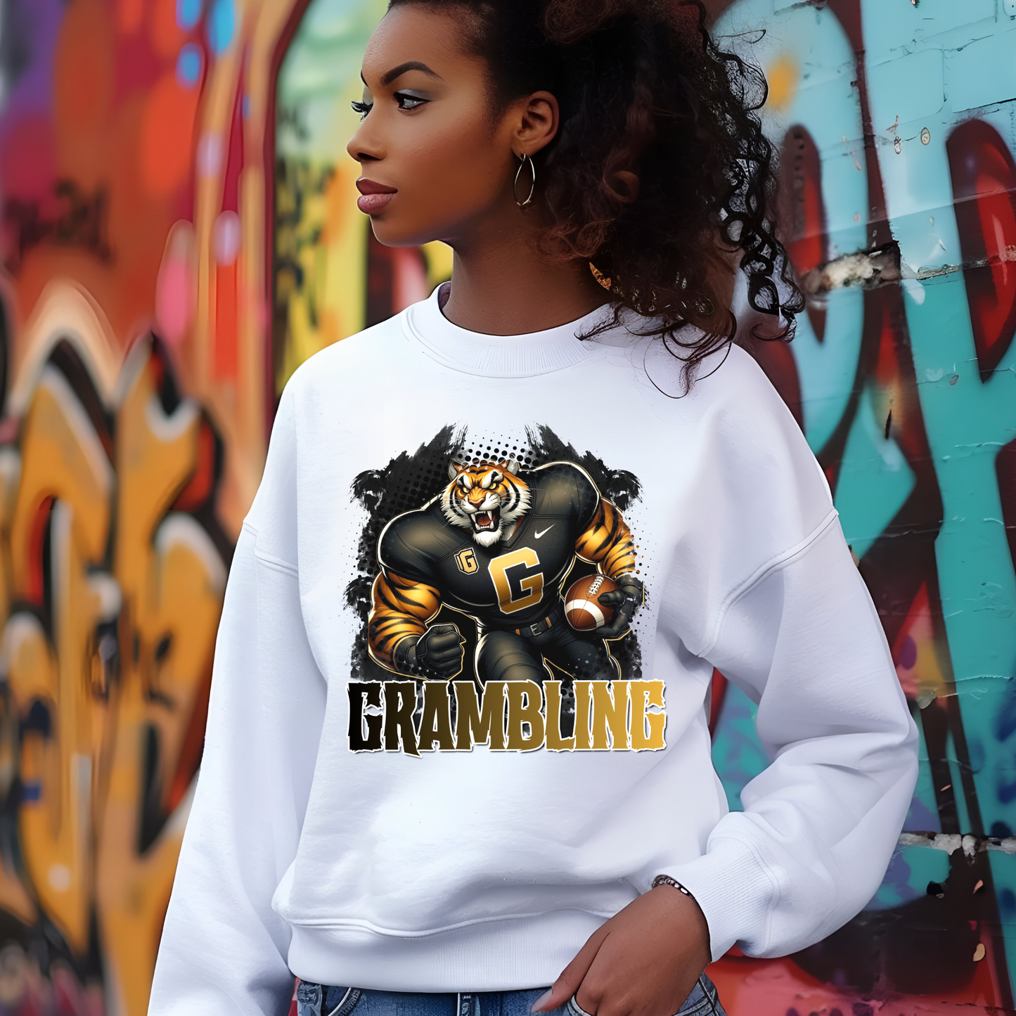Person wearing a white sweatshirt with a tiger graphic and 'Grambling' text in front of a graffiti wall.