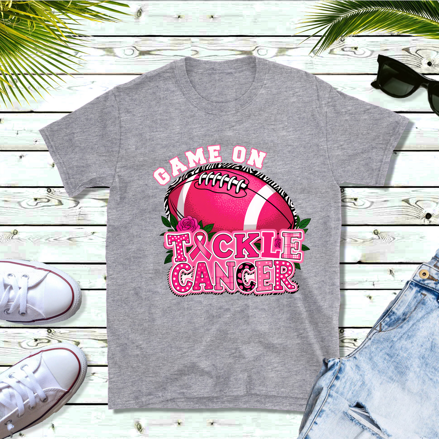 Gray t-shirt with 'Game On Tackle Cancer' design featuring a pink football on a wooden surface. Pink Out Football T-Shirt: Game On Tackle Awareness Support Tee