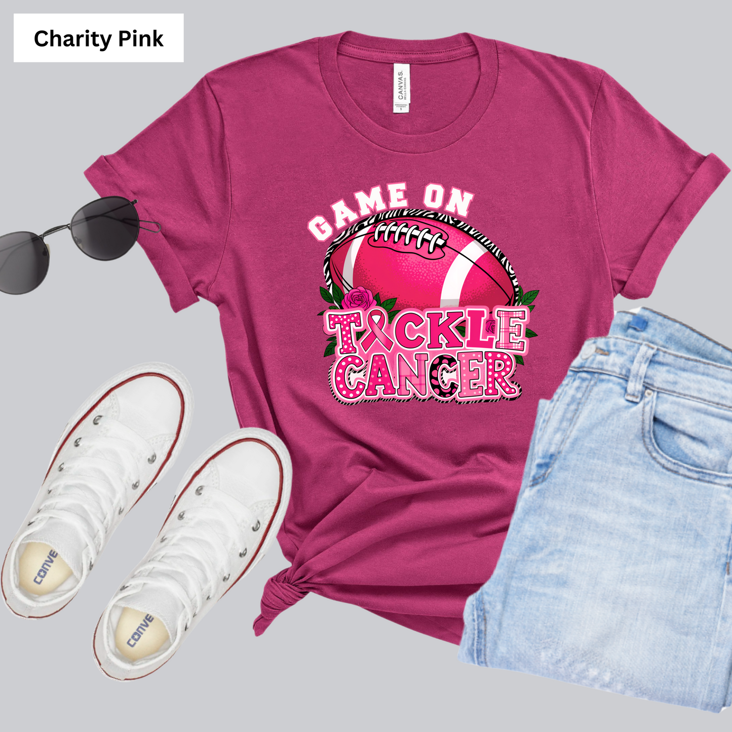 Pink t-shirt with 'Tackle Cancer' design, white sneakers, and sunglasses on a gray background Pink Out Football T-Shirt: Game On Tackle Awareness Support Tee