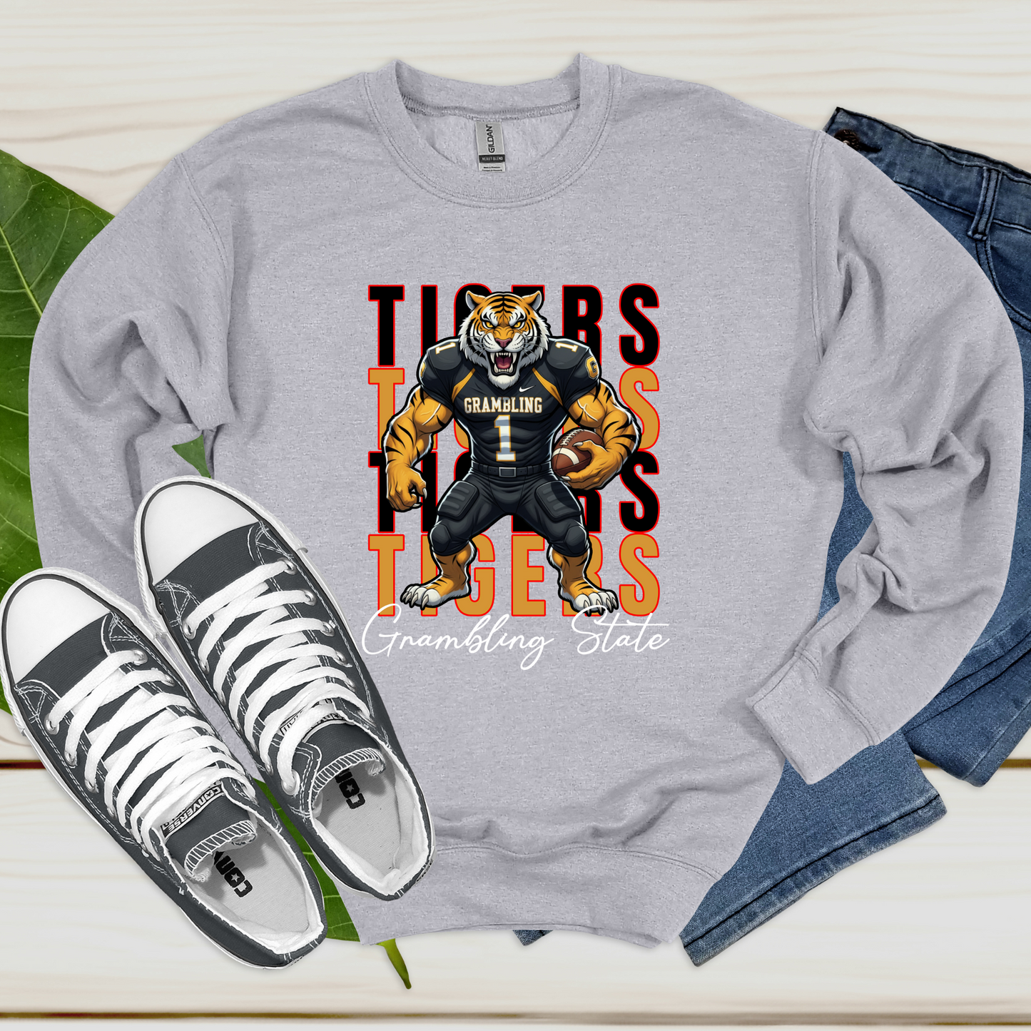 Gray sweatshirt with a tiger graphic and text, paired with sneakers and jeans on a light background Grambling Tigers Sweater: Tigers Homecoming Game Day Unisex Crewneck Sweater