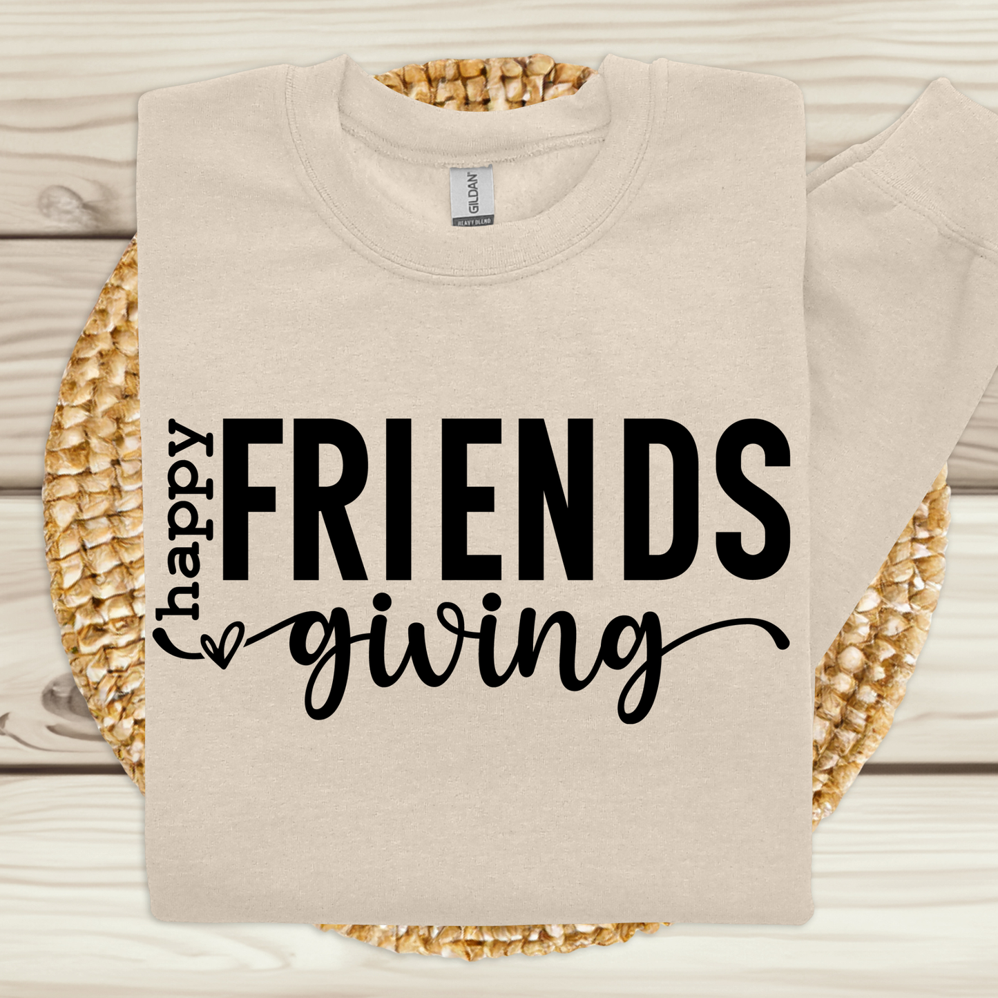 Beige sweatshirt with 'Happy Friendsgiving' text on a woven mat.
