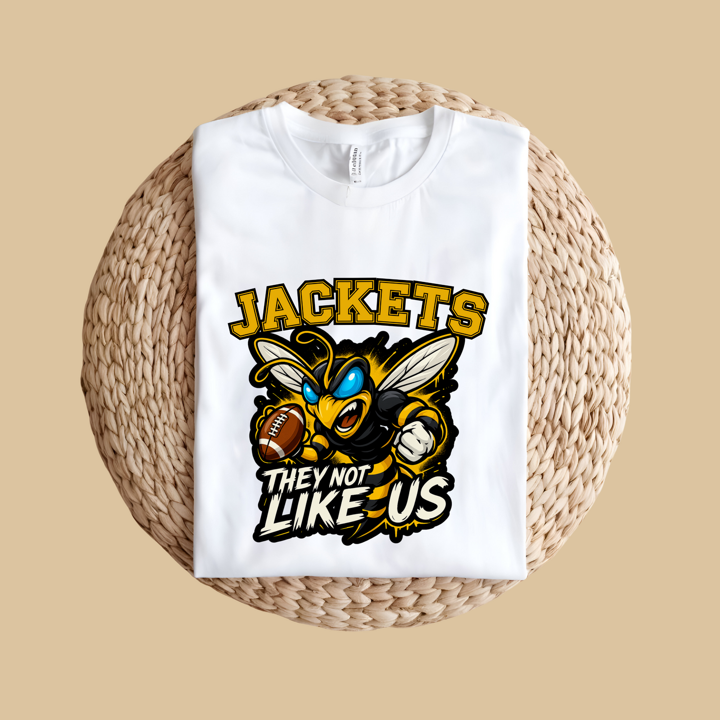 White t-shirt with a graphic design featuring a bee and text on a woven surface. Jackets Mascot Shirt - Bold Yellow Jacket They Not Like Us Game Day Tee