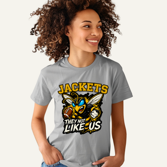 Person wearing a gray t-shirt with a 'JACKETS THEY NOT LIKE US' graphic design. Jackets Mascot Shirt - Bold Yellow Jacket They Not Like Us Game Day Tee