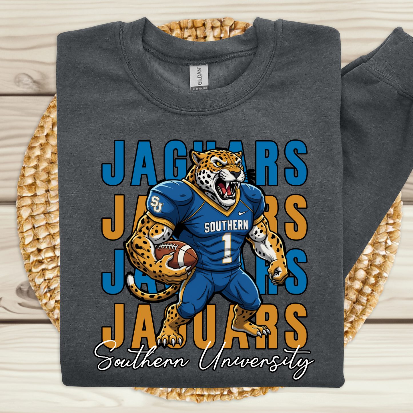Gray t-shirt with a jaguar graphic and 'Southern University' text on a woven mat. Southern Jaguars Sweatshirt: HBCU Game Day Football Cozy Sweater