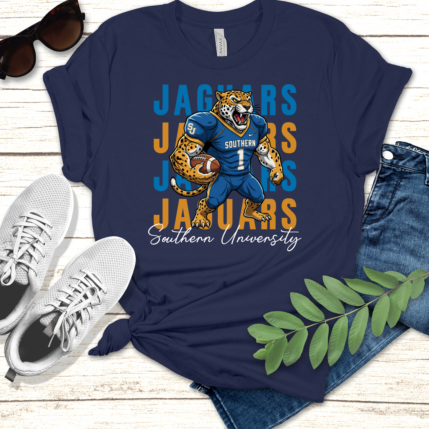 Navy blue t-shirt with Jaguars graphic design on a wooden surface with shoes and jeans. Southern Jaguars T-Shirt – Southern University Game Day & Homecoming Graphic Tee