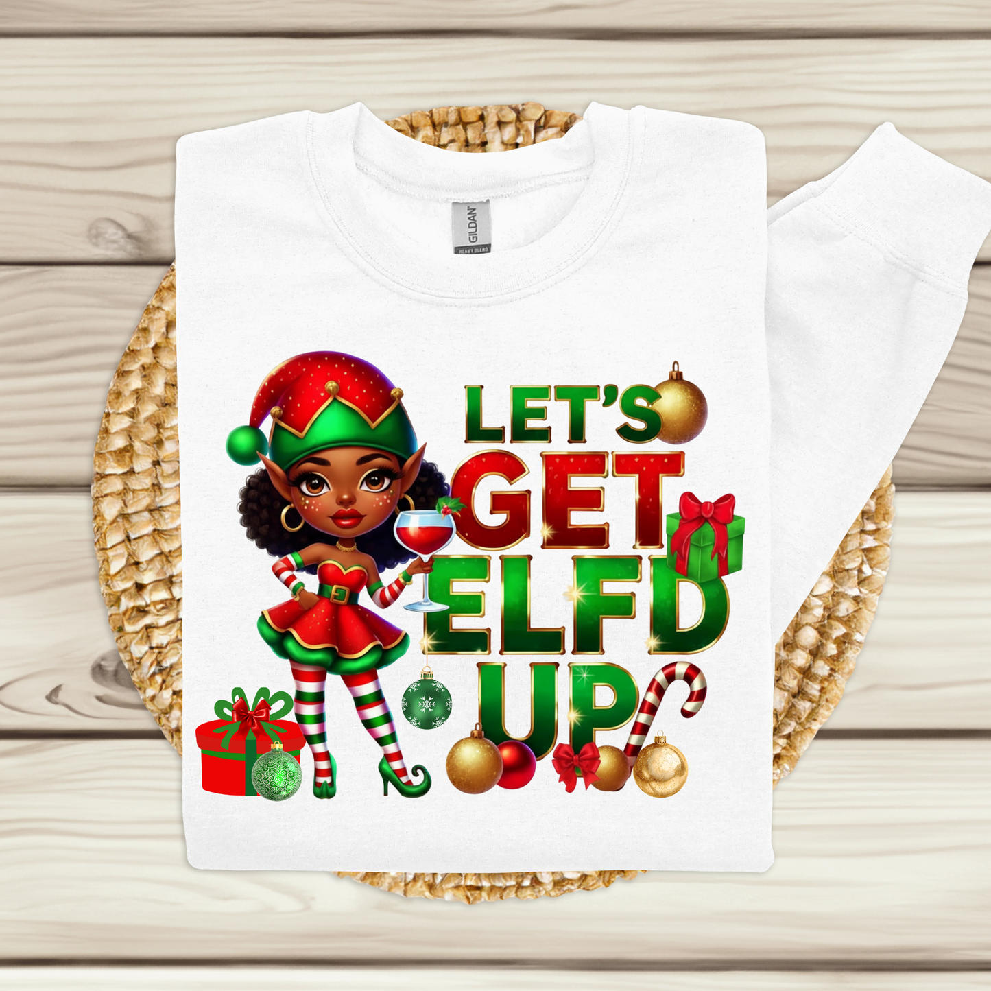 White t-shirt with Christmas-themed design featuring an elf and text on a wooden surface.