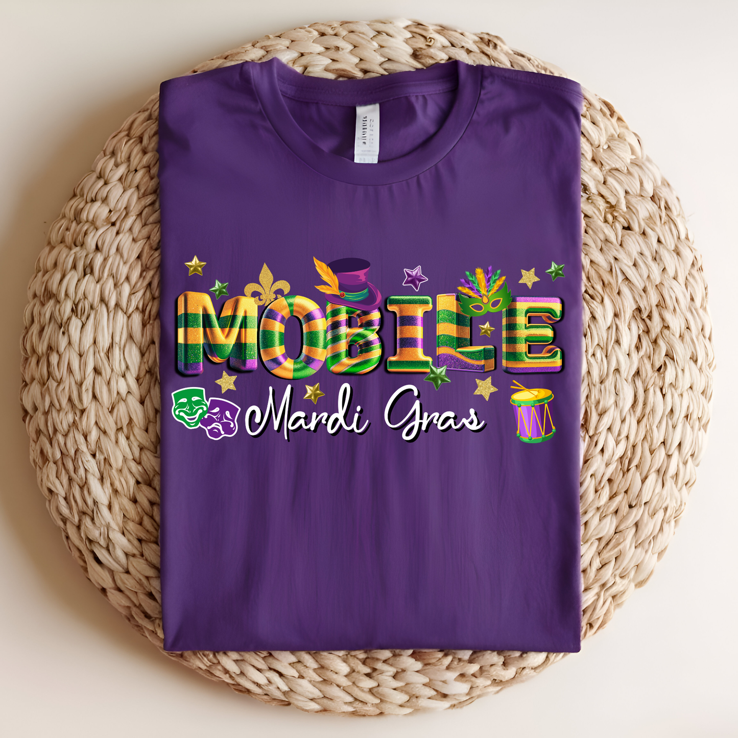 Purple t-shirt with Mardi Gras-themed design on a woven mat