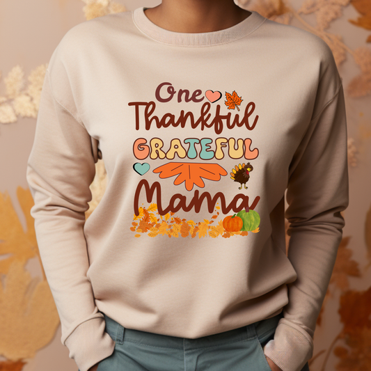 Beige sweatshirt with 'One Thankful Grateful Mama' text and fall-themed graphics on a neutral background. Retro Thanksgiving Sweatshirt "One Thankful Mama" Cozy Fall Mom Crewneck