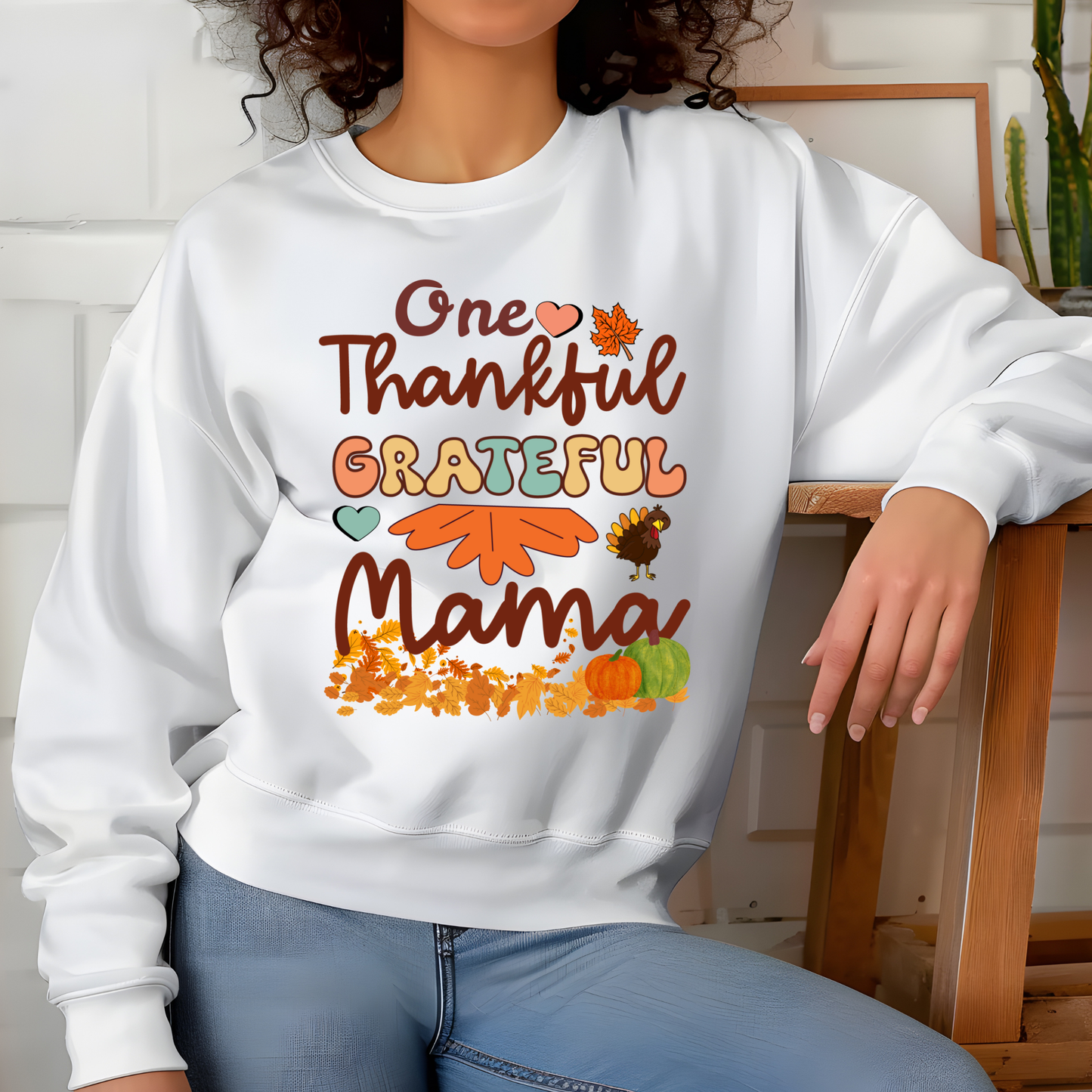 Person wearing a white sweatshirt with 'One Thankful Grateful Mama' text and fall-themed graphics.