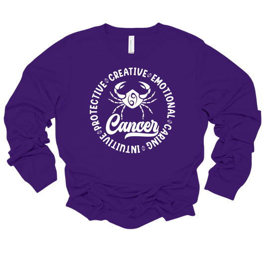 A purple long-sleeve crewneck sweatshirt featuring a white graphic print of a Cancer zodiac sign with the word 'Cancer' and surrounding adjectives.