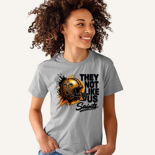 Woman wearing a gray t-shirt with a sports team graphic and text. Saints Mascot Shirt - Ultimate Saints Fan They Not Like Us Tee