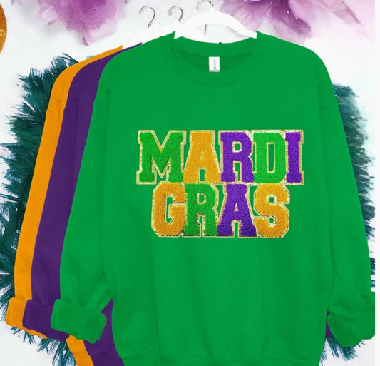 A green sweatshirt with 'MARDI GRAS' written in colorful chenille patches and glitter.