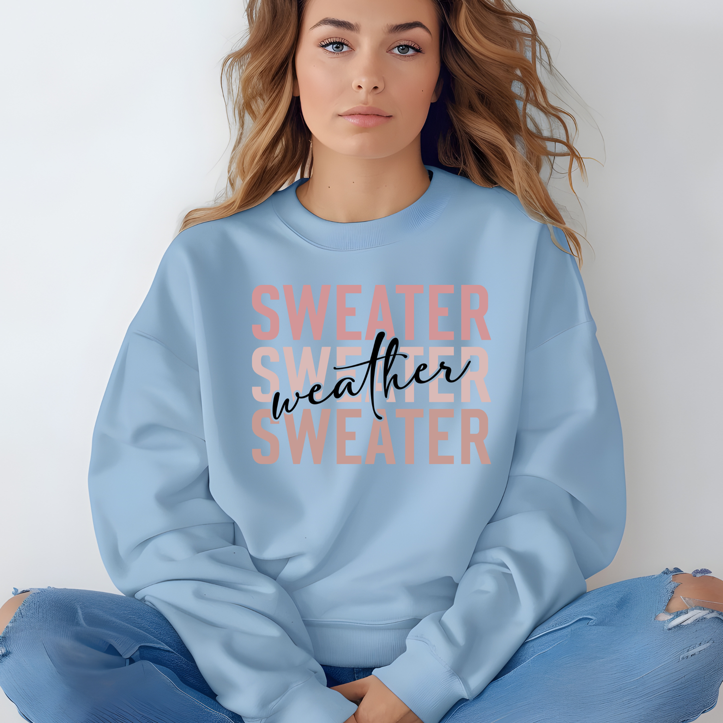 Woman wearing a light blue sweatshirt with 'SWEATER WEATHER SWEATERS' text. Sweater Weather - Cute and Chic Minimalist Fall Crewneck Cozy Sweater