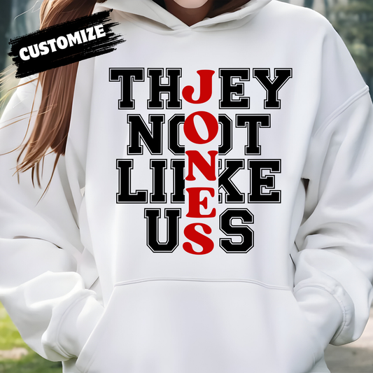 White hoodie with black and red text design, person wearing it outdoors. Family Reunion Hoodie - They Not Like Us - Custom Family Name Matching Hoodie