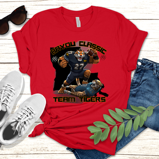 Red t-shirt with 'BAYOU CLASSIC TEAM TIGERS' graphic design on a wooden surface with sunglasses, shoes, and jeans. Bayou Classic Team Tigers: Grambling Tigers Bayou Classic Game Day T-Shirt