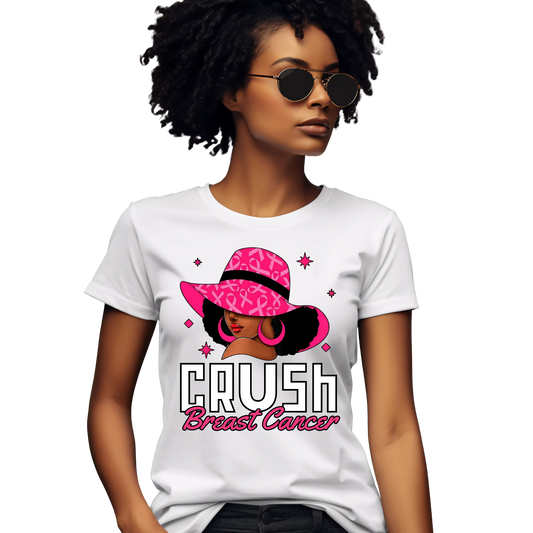 A woman wearing a white graphic T-shirt with a pink and black illustration of a woman in a pink hat and the text 'CRUSH Breast Cancer'.