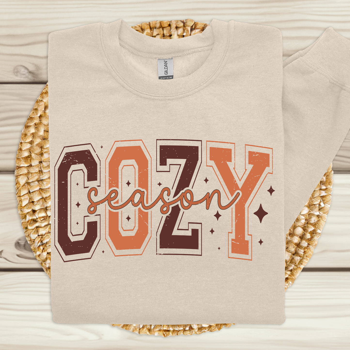 Beige sweatshirt with 'COZY season' text on a woven mat Cozy Season Sweatshirt: Fall Vibe Retro Block Letter Crewneck Sweater