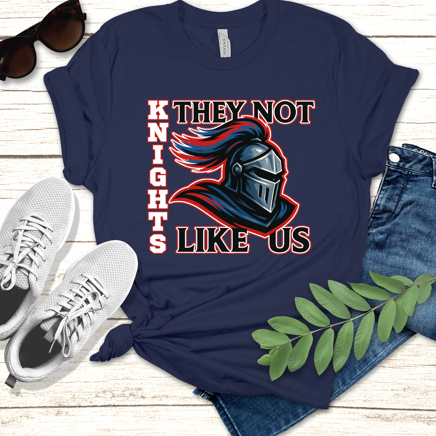 Navy blue t-shirt with a graphic design and text on a wooden surface with shoes and jeans. Knight Game Day Shirt: They Not Like Us - Knights Team Spirit Tee's