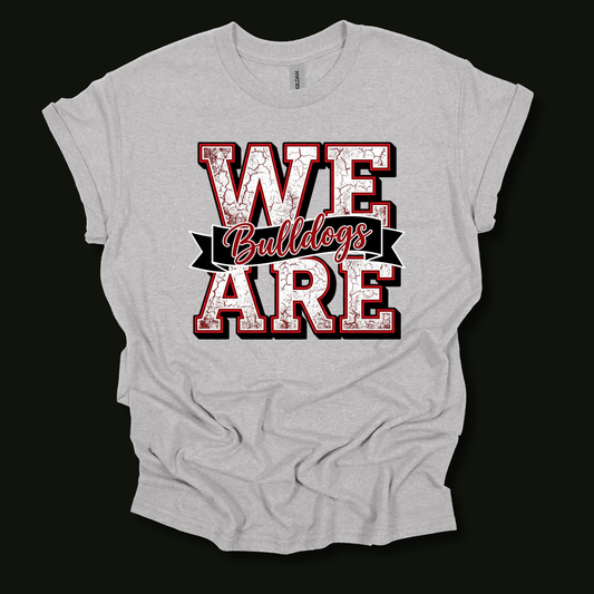 A light heather gray t-shirt with a distressed graphic reading 'WE ARE Bulldogs' in red and white, displayed against a solid black background.
