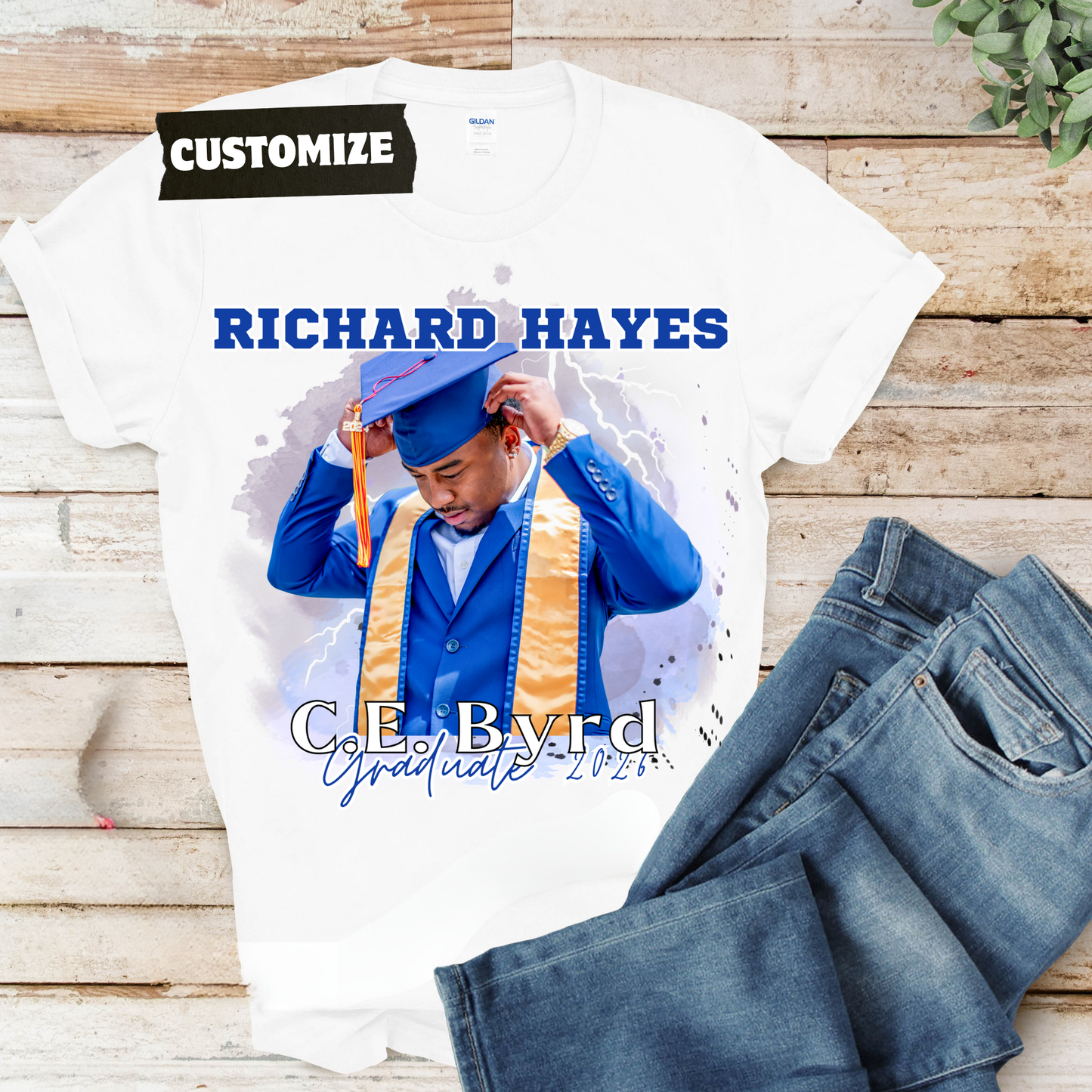 Graduation-themed t-shirt with personalized text on a wooden surface  Customizable graduation photo t-shirt featuring senior portrait, school mascot, and sports organization logos in school colors