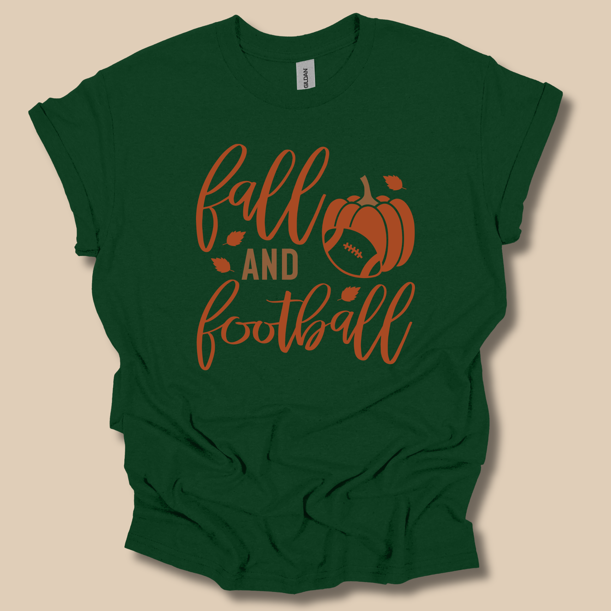 A cream-colored t-shirt with a retro-style autumn graphic that reads 'Always Be BE Thankful' in orange and teal lettering, decorated with a turkey, acorn, maple leaf, and small flowers, displayed against a solid brown background.
