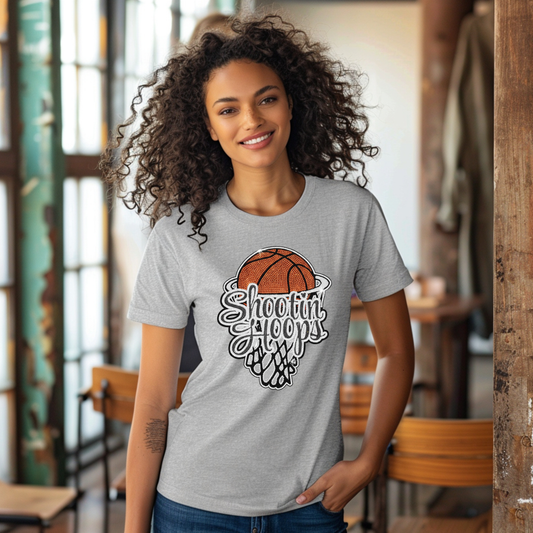 Woman wearing a gray t-shirt with a basketball design and text, standing in a casual indoor setting.